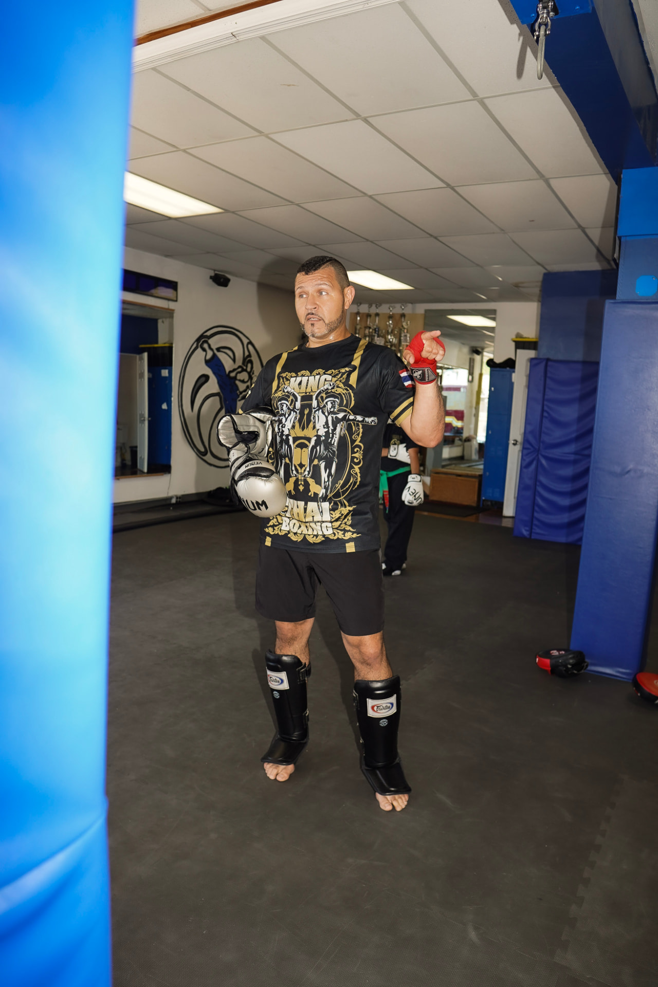 Coach holding boxing gloves and shin guards before training